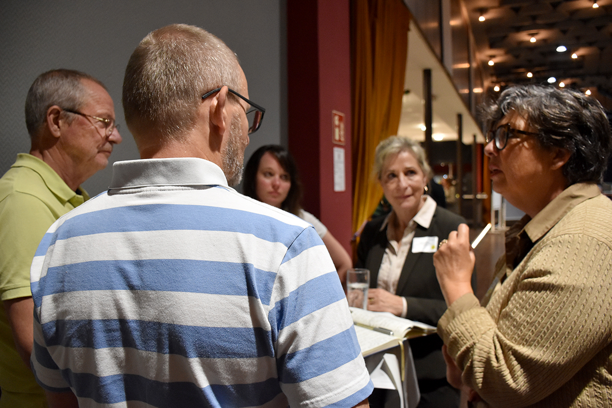 Fünf Personen stehen um einen Tisch und reden miteinander. (Quelle: Ellen Boettcher) Fünf Personen stehen um einen Tisch und reden miteinander.