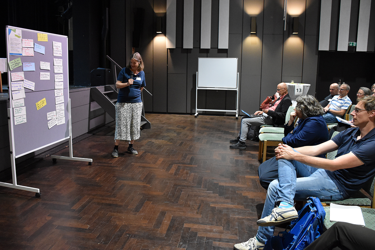 Miranda Schreurs, Ko-Vorsitzende des NBG, steht vor der Bühne und erklärt die Notizen an einer Pinnwand. (Quelle: Ellen Boettcher) Miranda Schreurs, Ko-Vorsitzende des NBG, steht vor der Bühne und erklärt die Notizen an einer Pinnwand.